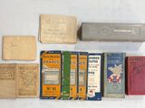 de nombreux livres anciens posés sur une table, à côté d'une boîte d'allumettes