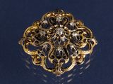 une image représentant une broche en or et diamants sur un fond bleu