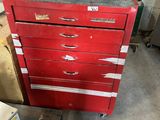a red chest of drawers in a garage next to a machine