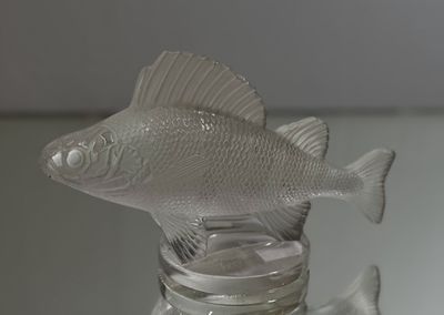 a glass bottle with a fish in it on a table