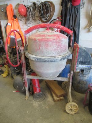 une bétonnière rangée dans un garage avec d'autres outils