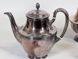 two silver teapots sitting next to each other on a table