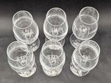 six empty wine glasses sitting on a table with a black background