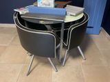 une petite table avec deux chaises et un ordinateur portable posé dessus