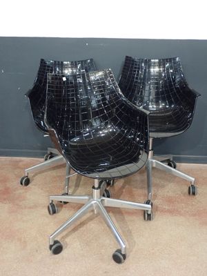 two black chairs sitting on top of each other next to a wall