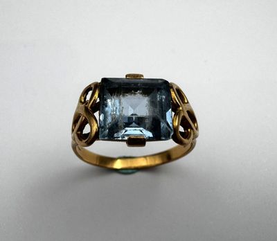 Gros plan sur une bague en or ornée d'une topaze bleue