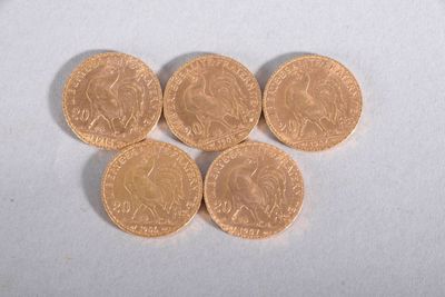 four gold coins sitting on top of each other on a white surface