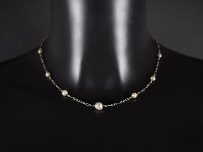 a close up of a mannequin wearing a necklace with pearls on it