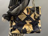 a mannequin holding a handbag with a scarf on it