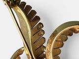 a gold brooch with a feather on it