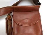 brown leather purse on white background with strap and shoulder strap