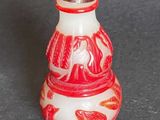a small red and white vase with a bird on it