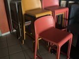 Dans un restaurant, des chaises aux couleurs vives sont alignées contre un mur