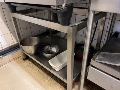 a metal shelf with pots and pans on it in a kitchen