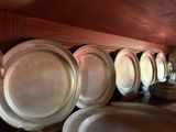 many silver plates lined up on a shelf in a room