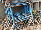 a pile of old blue chairs sitting on the side of a building