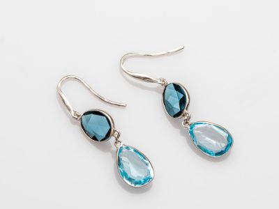 une paire de boucles d'oreilles en topaze bleue et en topaze blanche sur fond blanc