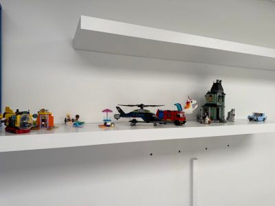 une étagère blanche sur laquelle se trouvent des Lego et un hélicoptère