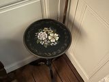 une petite table ornée d'un motif floral, placée devant une porte