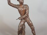 statue en bronze représentant un homme tenant une épée, posée sur un socle en bois