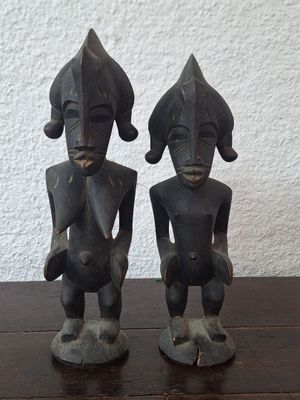 pair of wooden statues of a man and a woman sitting on a table