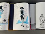 three books with drawings of people on them on a table
