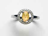 une bague ornée d'un saphir jaune ovale et de diamants, sur fond blanc