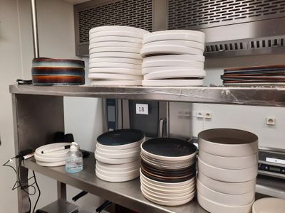 de nombreuses assiettes et casseroles empilées sur une étagère dans la cuisine