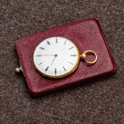 une montre de poche posée sur un étui rouge