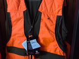 un gilet orange muni d'une étiquette, suspendu dans un placard