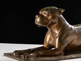 bronze statue of a dog laying on a white surface