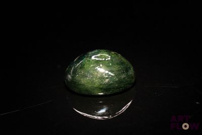 a green rock sitting on a black surface
