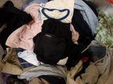 a pile of clothes on a bed next to a bag