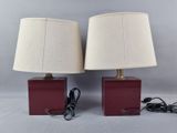pair of red and gold table lamps with white lampshads on them