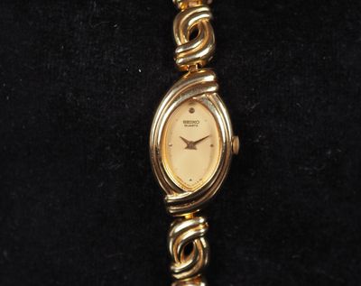 a close up of a gold watch on a black surface