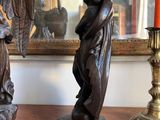 two statues of angels on a table next to a candle