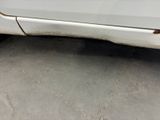 a white car that has rust on the side of it