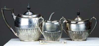 three silver teapots sitting on a white table