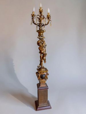 an image of a tall candle holder with a statue on top of it