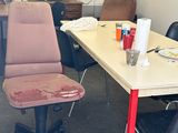 a desk with a chair and a fan in a room