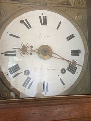 clock with roman numerals on the face of it in a glass case
