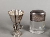 a silver cup and a silver salt shaker on a table