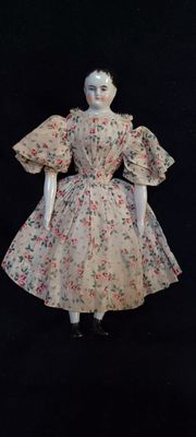 une poupée qui porte une robe à fleurs
