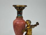 a small statue of a boy holding a vase