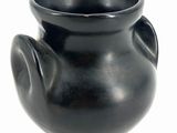 a black vase that is sitting on a white surface