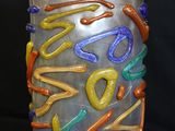 a vase that has a lot of different colored letters on it