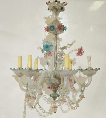 a chandelier with flowers and candles hanging from it