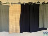 trois paires de pantalons suspendues à un portant devant un mur