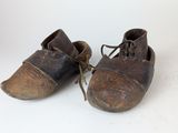 une vieille paire de chaussures à lacets posée sur une surface blanche