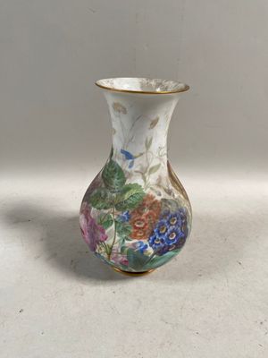 un petit vase décoré de fleurs, posé sur une table